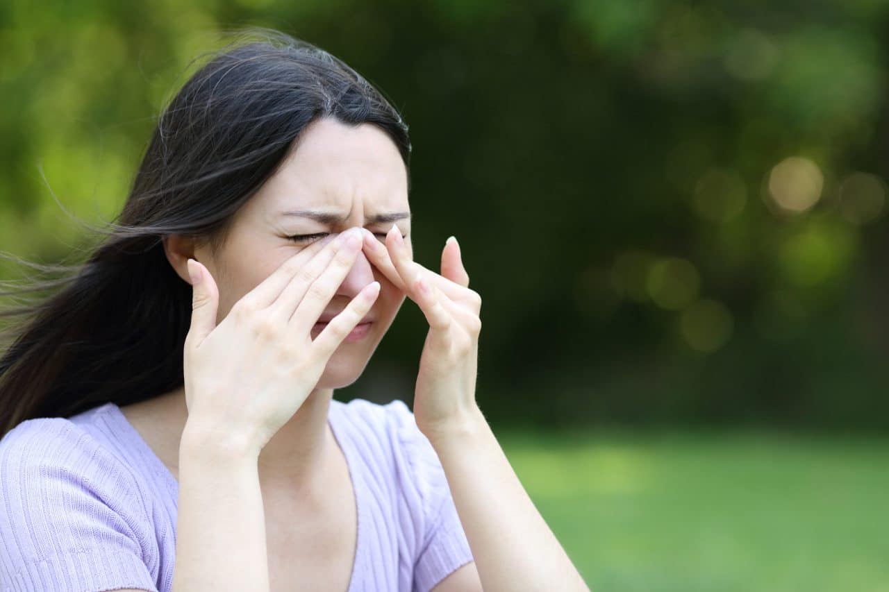 A woman experiencing sinus congestion outside.