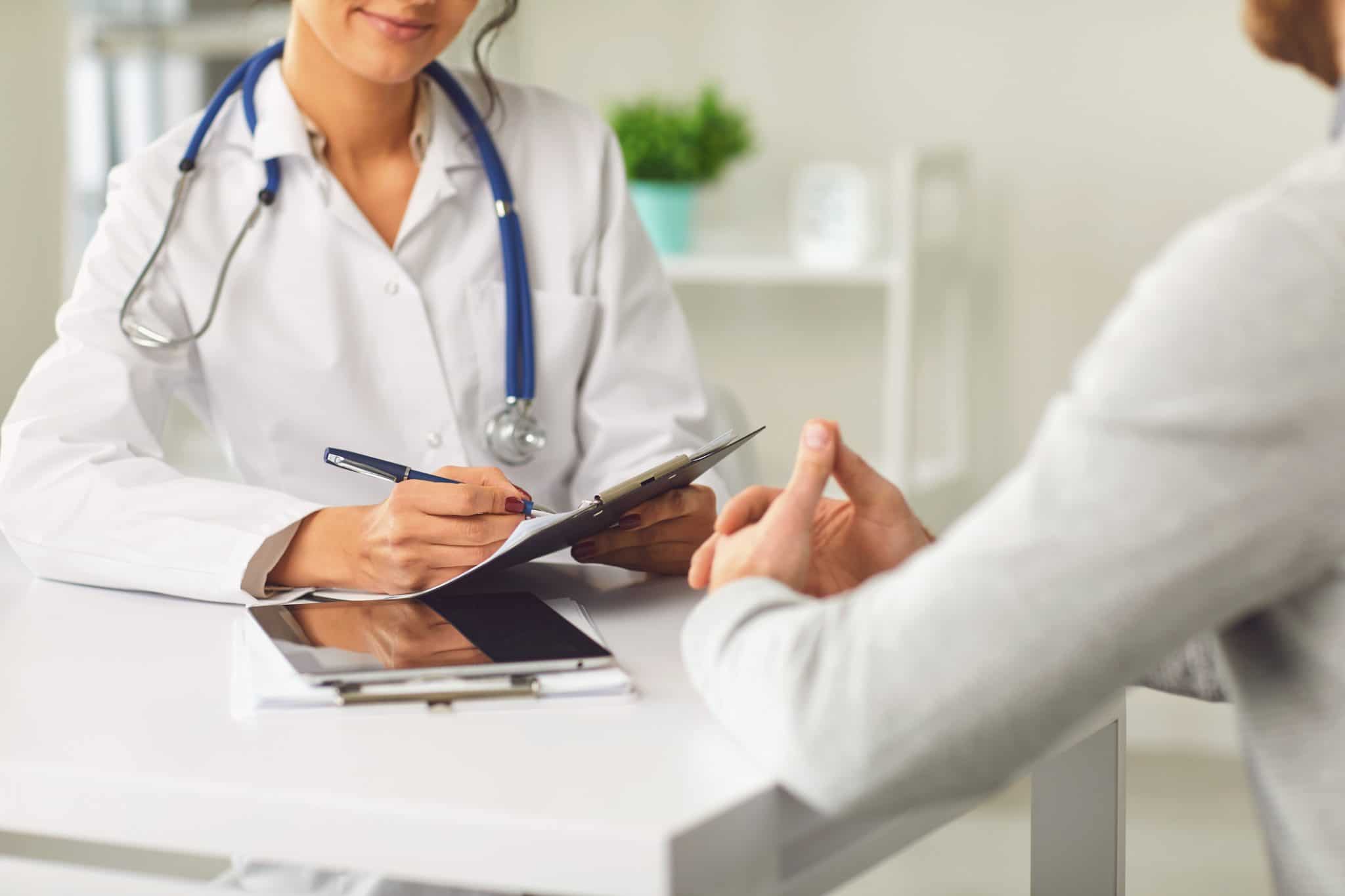 Doctor and patient talk together in a clinical setting.