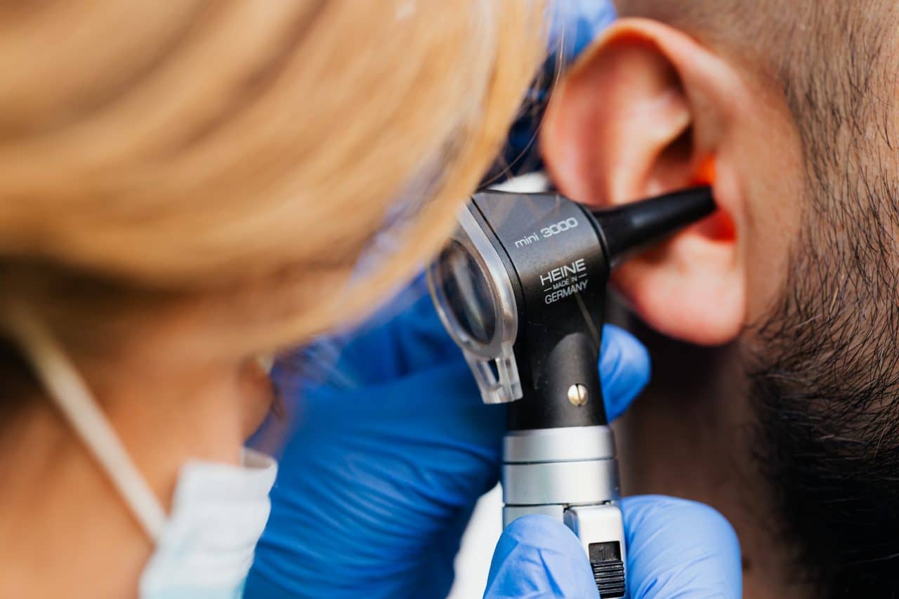 Medical professional examining a man's ear.
