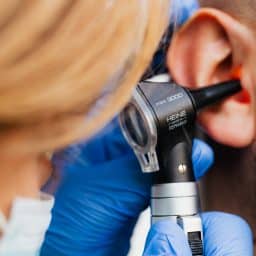 Medical professional examining a man's ear.