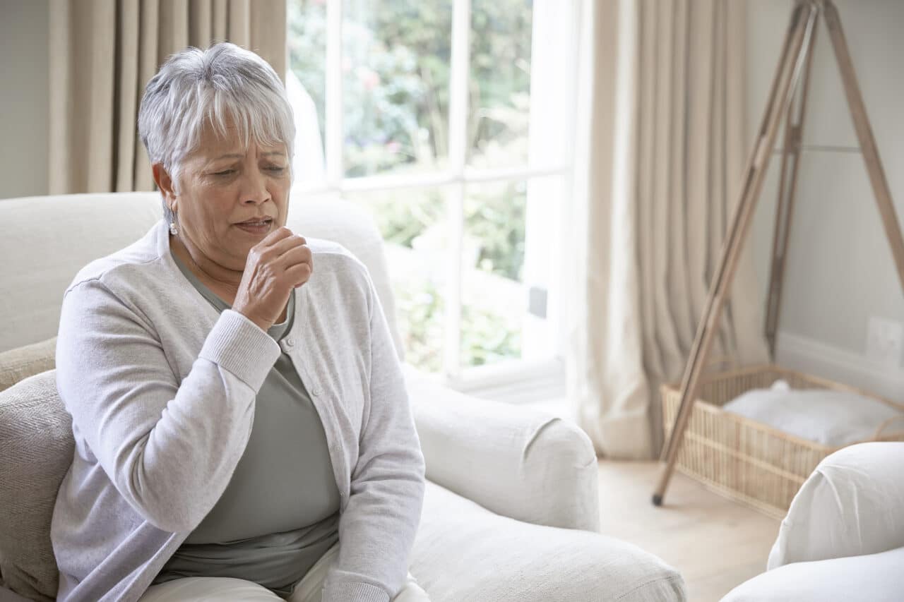 Older woman coughing at home.