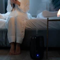 Woman with a humidifier next to her bed.