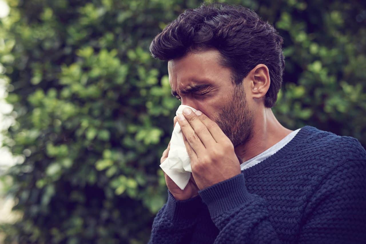 a man blows his nose outdoors