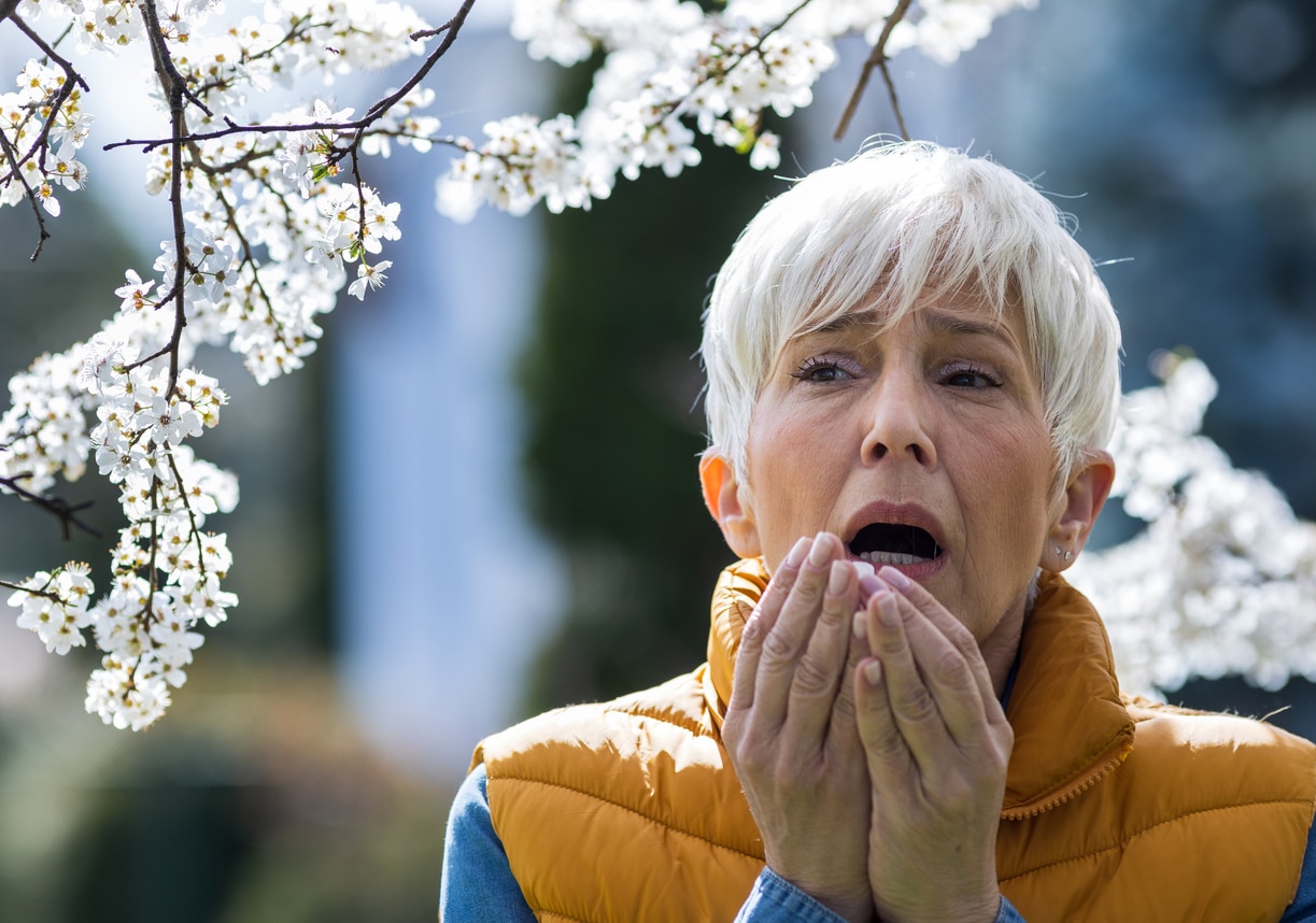 Woman sneezing in the park from allergies