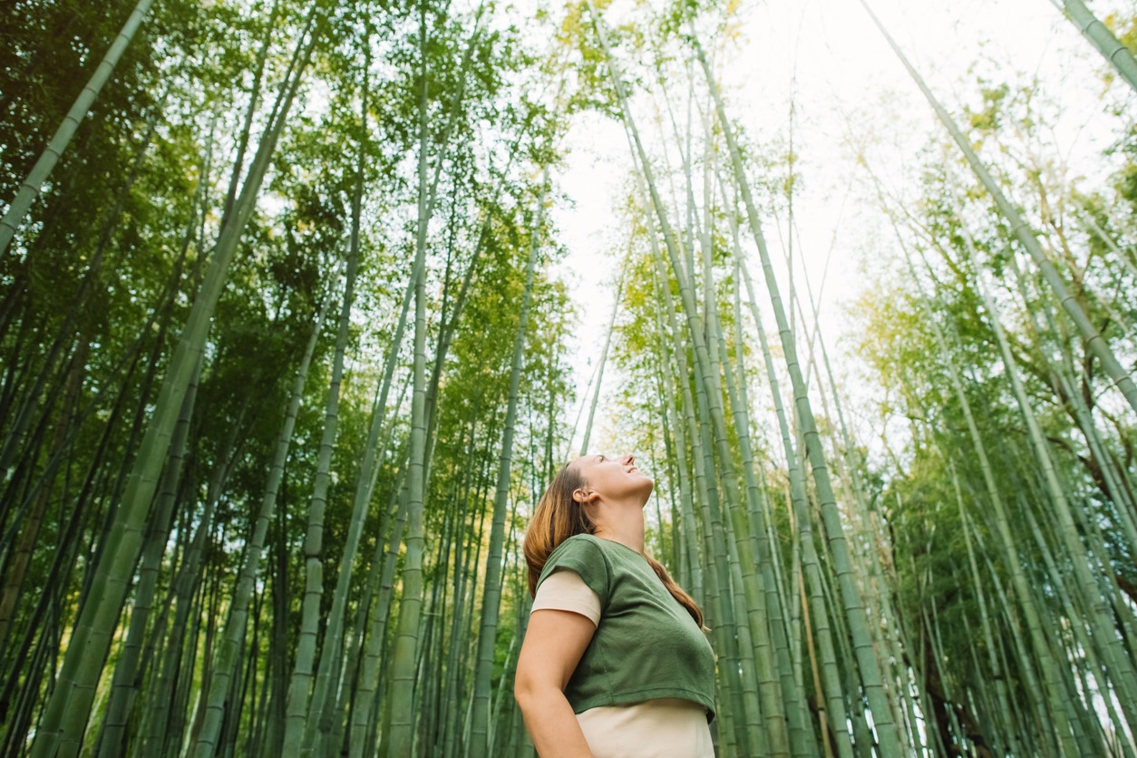 Woman standing in a bamboo forest enjoying earth day.