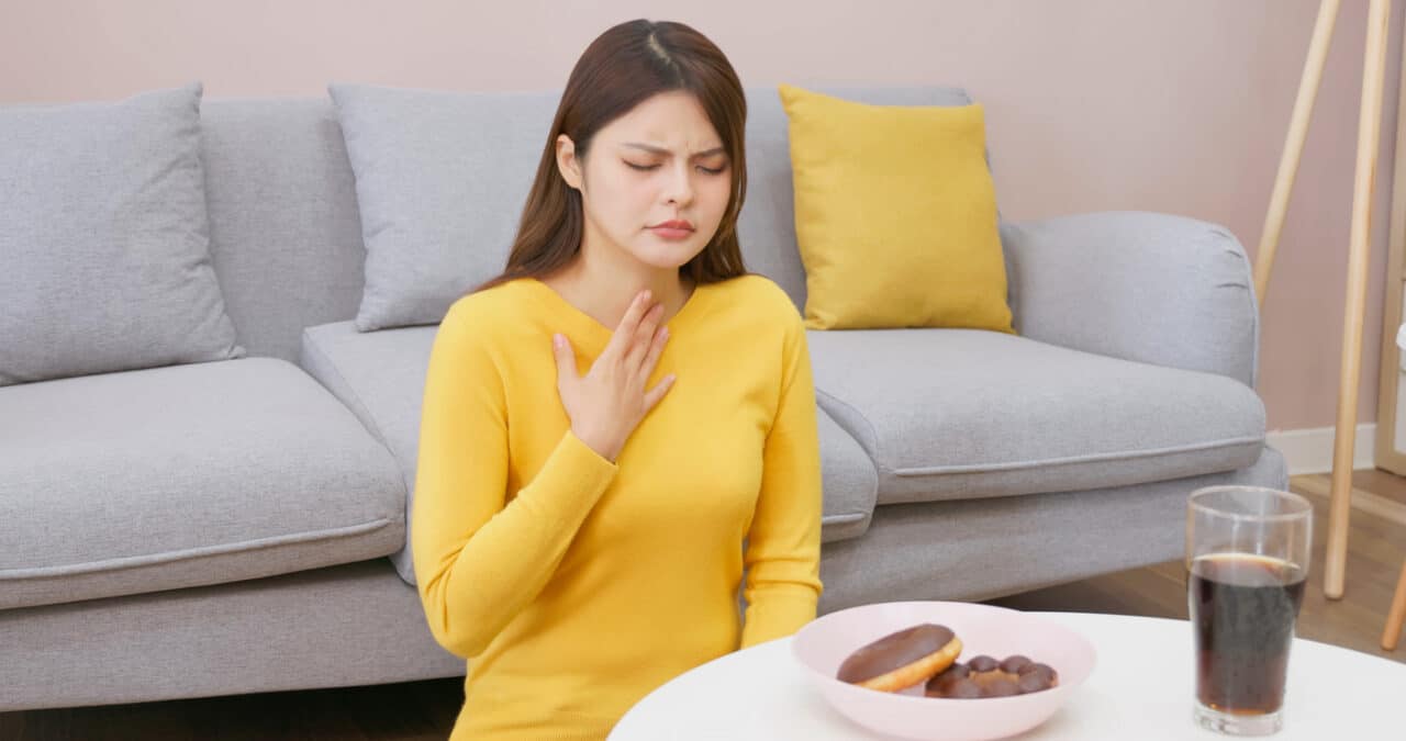 Woman with acid reflux holding her throat.