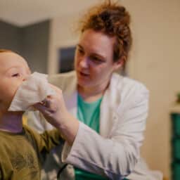 Pediatrician holding a tissue to a young boy's nose