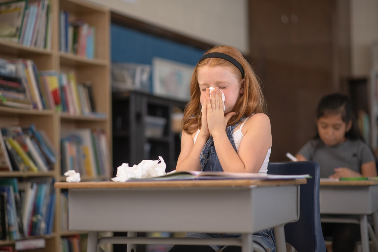 Young girl blows her nose 