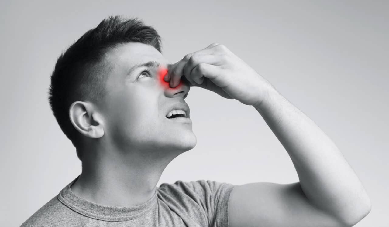 Young man suffering from nose pain. black and white.