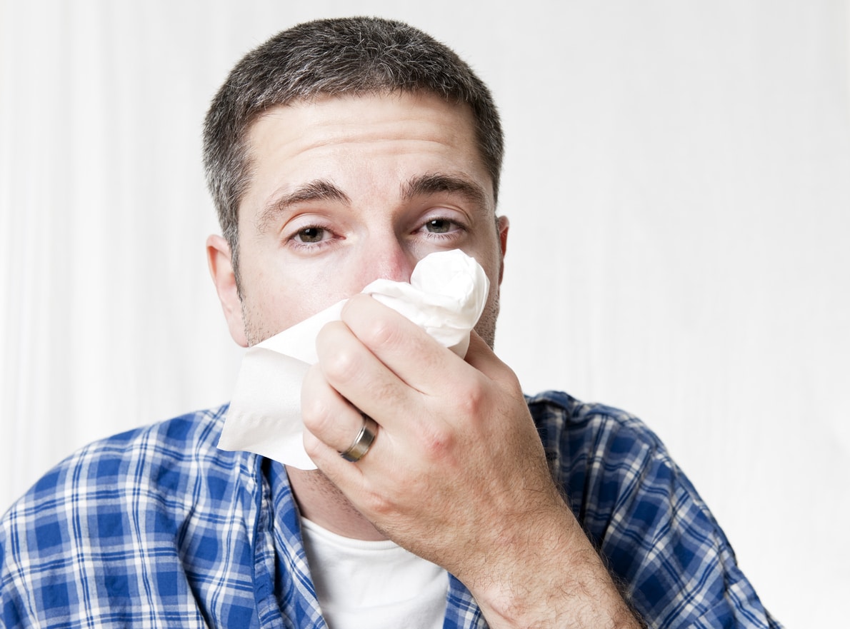 Man blowing his nose into a tissue