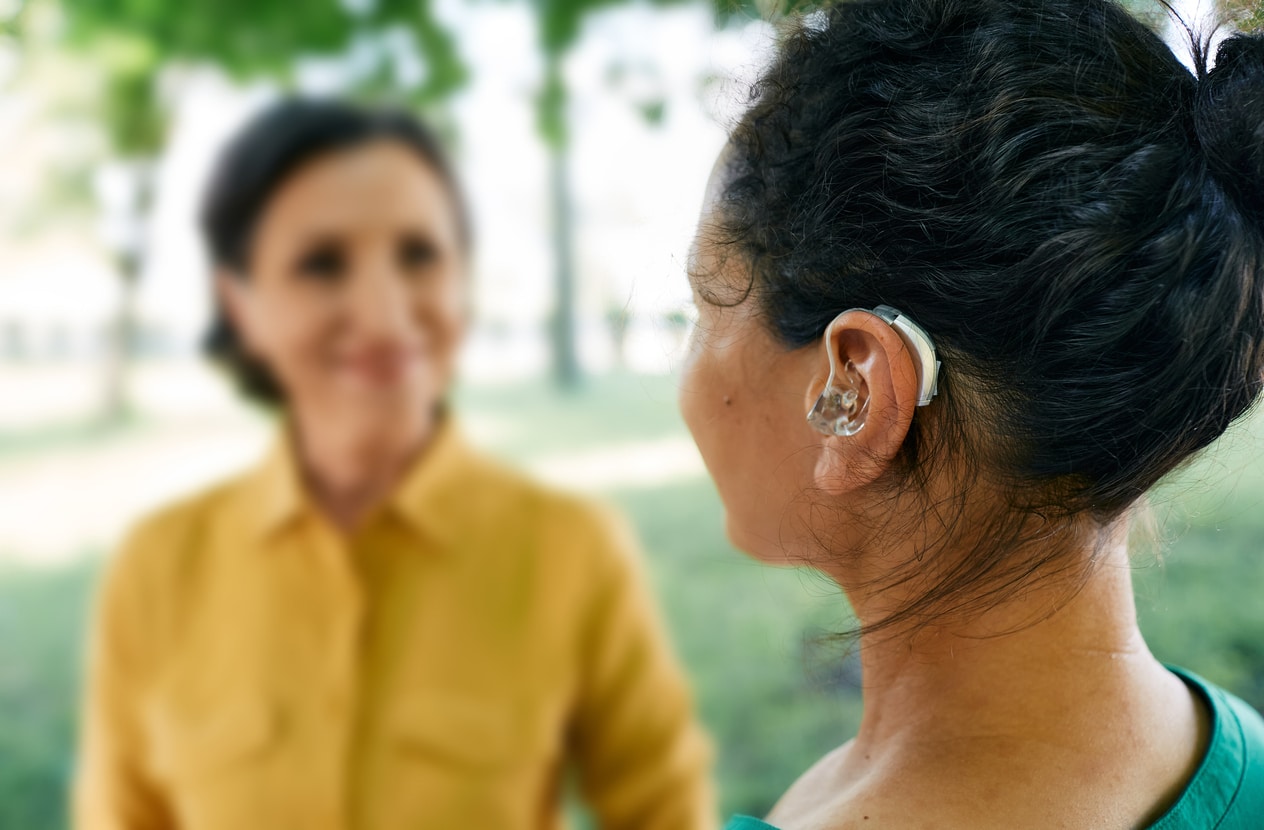 Woman with hearing aid chats in park