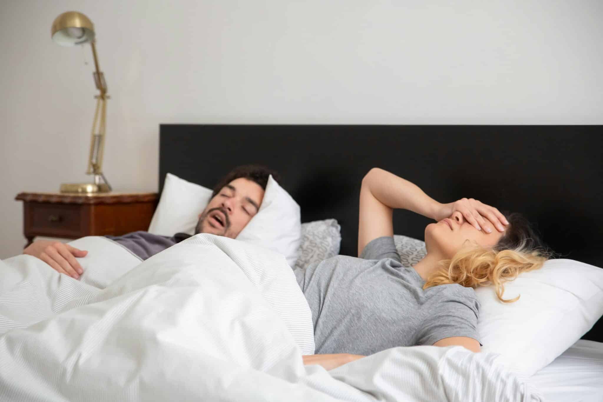 Couple with sleep apnea trying to sleep; one of them snores loudly and the other struggles to sleep